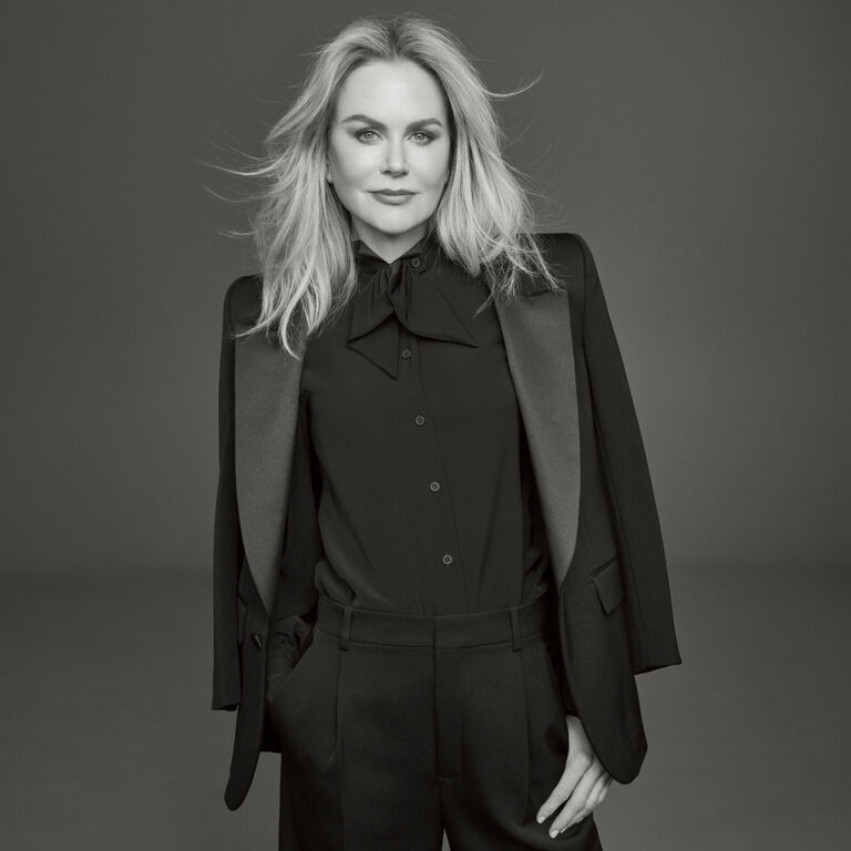 Photo of Clé de Peau Beauté’s new global brand ambassador, Nicole Kidman, wearing a black suit with right hand in pocket, looking directly at the camera in a monochrome image.