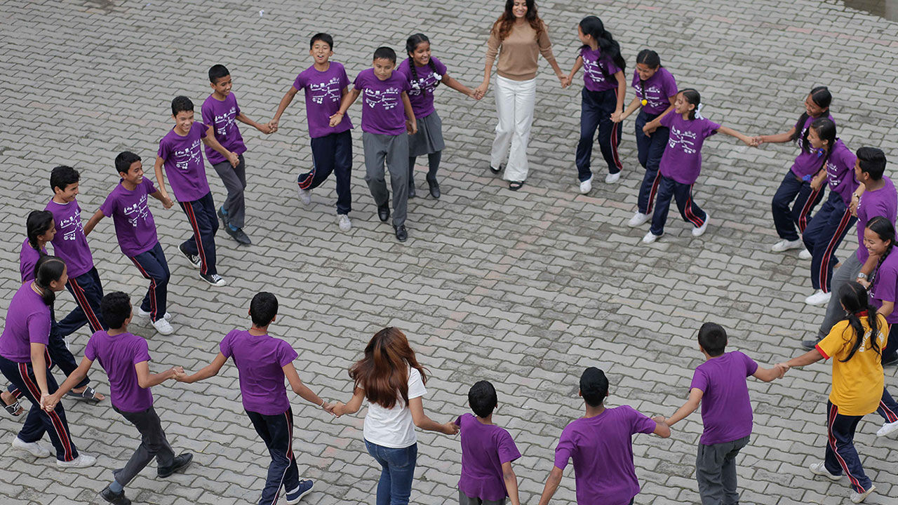 Photo of Binita Shrestha and Pratiksha Pandey standing in a circle and holding hands with a group of students.