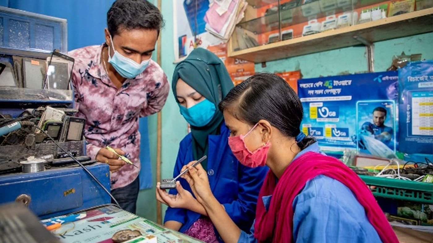 Photo of a man and two women wearing face masks are reparing electronic devices.