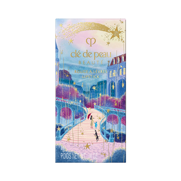 Photo of the 26 AW Holiday Collection limited-edition LIPSTICK outer box. The rectangular package features a scenic illustration of figures on a path under a starry sky with a castle, decorated with a large gold shooting star across the top.