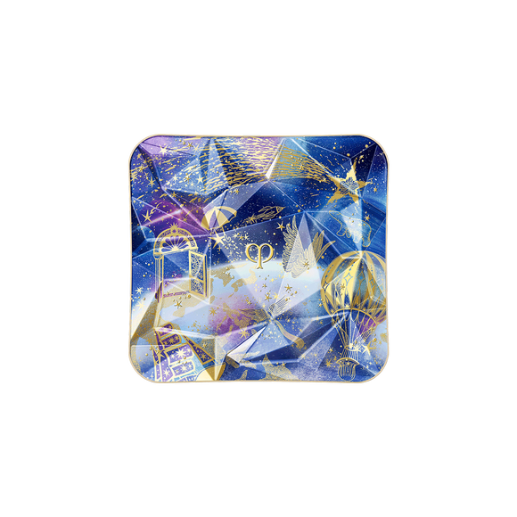 Photo of the 26 AW Holiday Collection limited-edition THE LUMINIZING FACE ENHANCER case. The blue and purple prismatic compact lid features a geometric multi-faceted design detailed with gold illustrations of a door, a hot air balloon, and a shooting star.