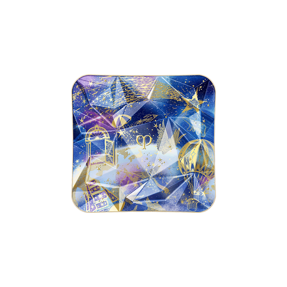 Photo of the 26 AW Holiday Collection limited-edition THE LUMINIZING FACE ENHANCER case. The blue and purple prismatic compact lid features a geometric multi-faceted design detailed with gold illustrations of a door, a hot air balloon, and a shooting star.