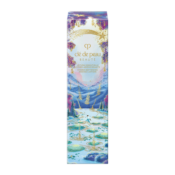 Photo of the 26 AW Holiday Collection limited-edition HYDRO-SOFTENING ESSENCE LOTION outer box. The package shows a person stepping on stones across a blue lake with gold ripples, decorated with a gold shooting star and purple trees at the top.