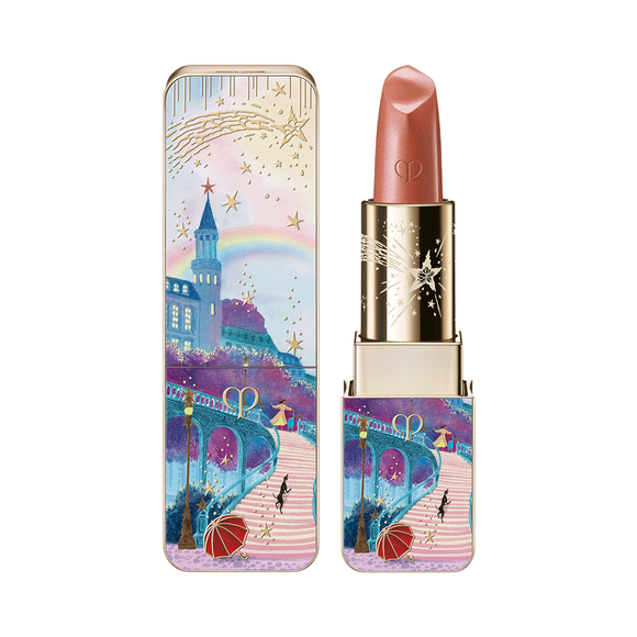 Photo of the 26 AW Holiday Collection limited-edition LIPSTICK. A highly detailed scenic illustration of a path toward a castle with a rainbow and two figures is depicted on the square-tubed gold bullet. The lipstick is shown open beside its matching outer case and a texture swatch.