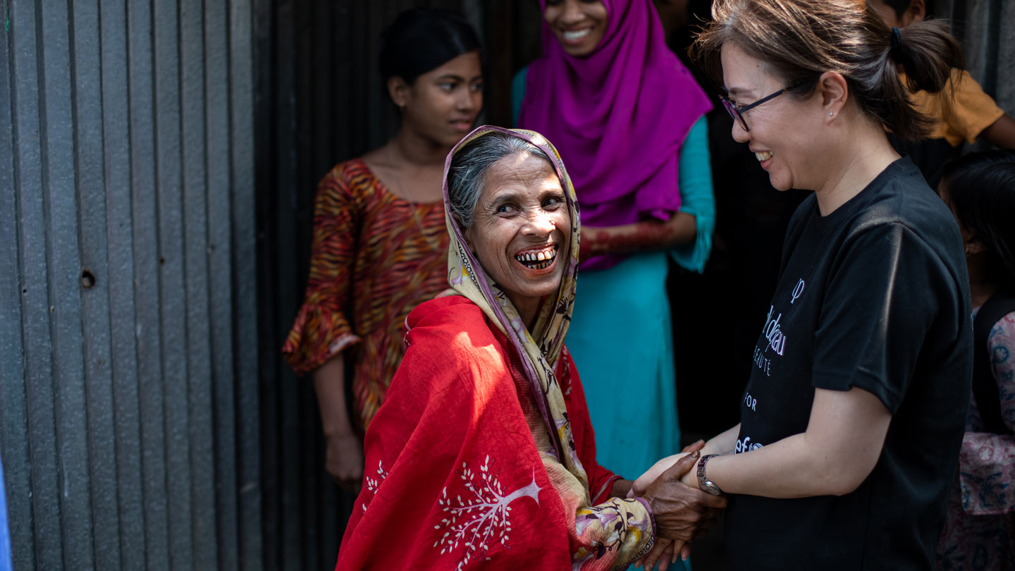 Photo of Ms. Mizuki Hashimoto warmly shaking hands and smiling with the mother of an Alternative Learning Program beneficiary.