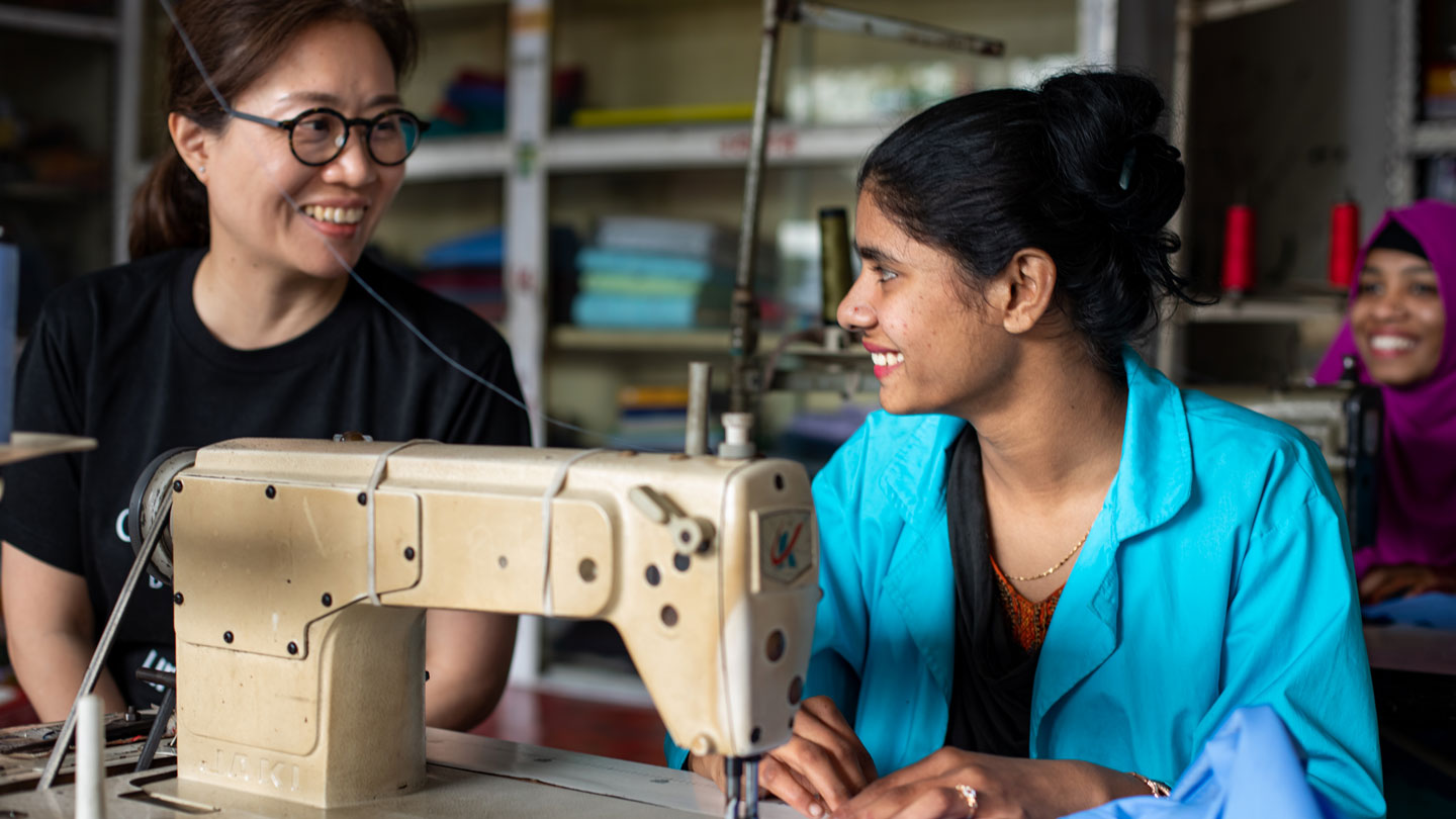 Photo of Ms. Miyuki Hashimoto and a woman talking in front of a sewing machine.