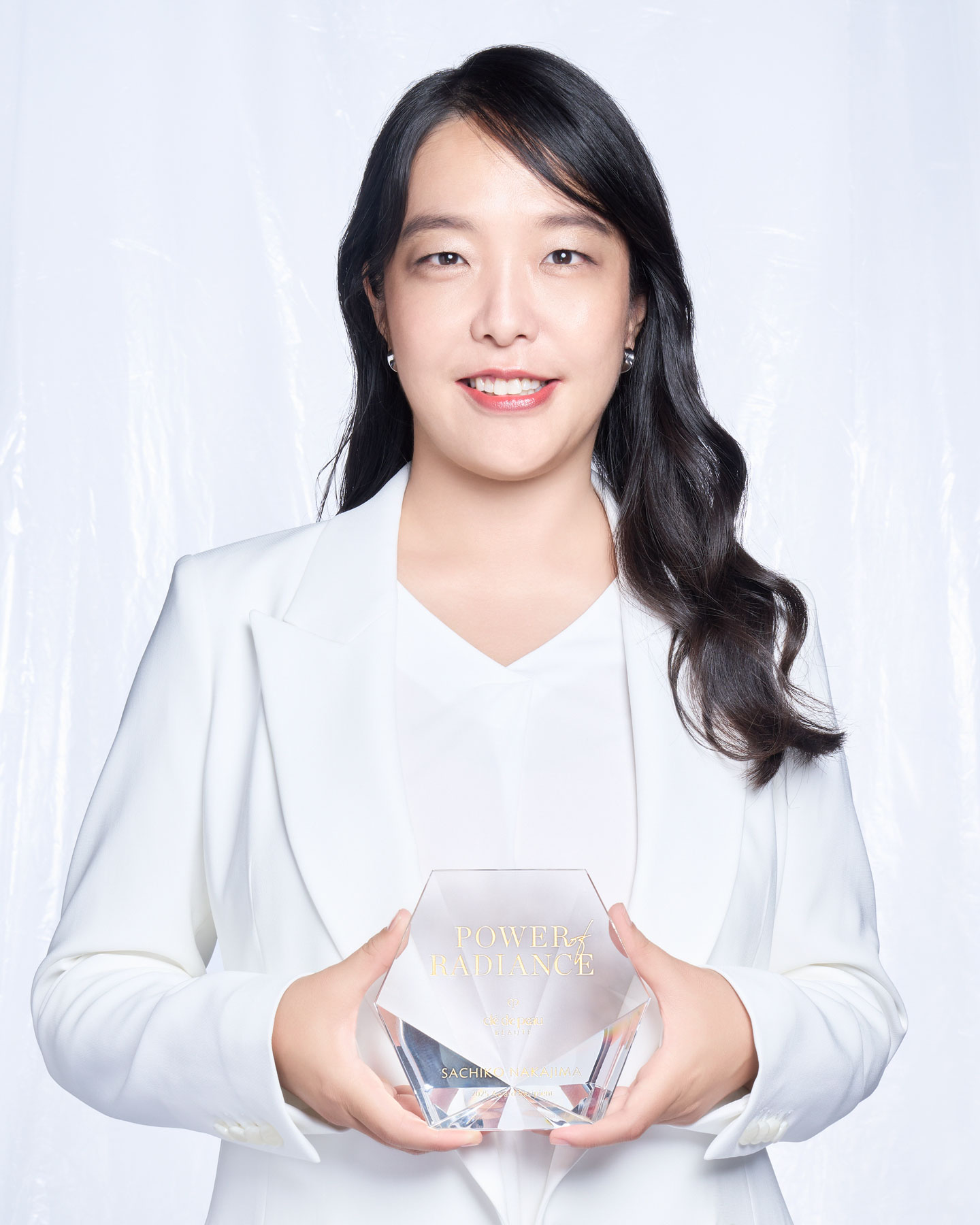 Photo of Sachiko Nakajima holding a crystal trophy.
