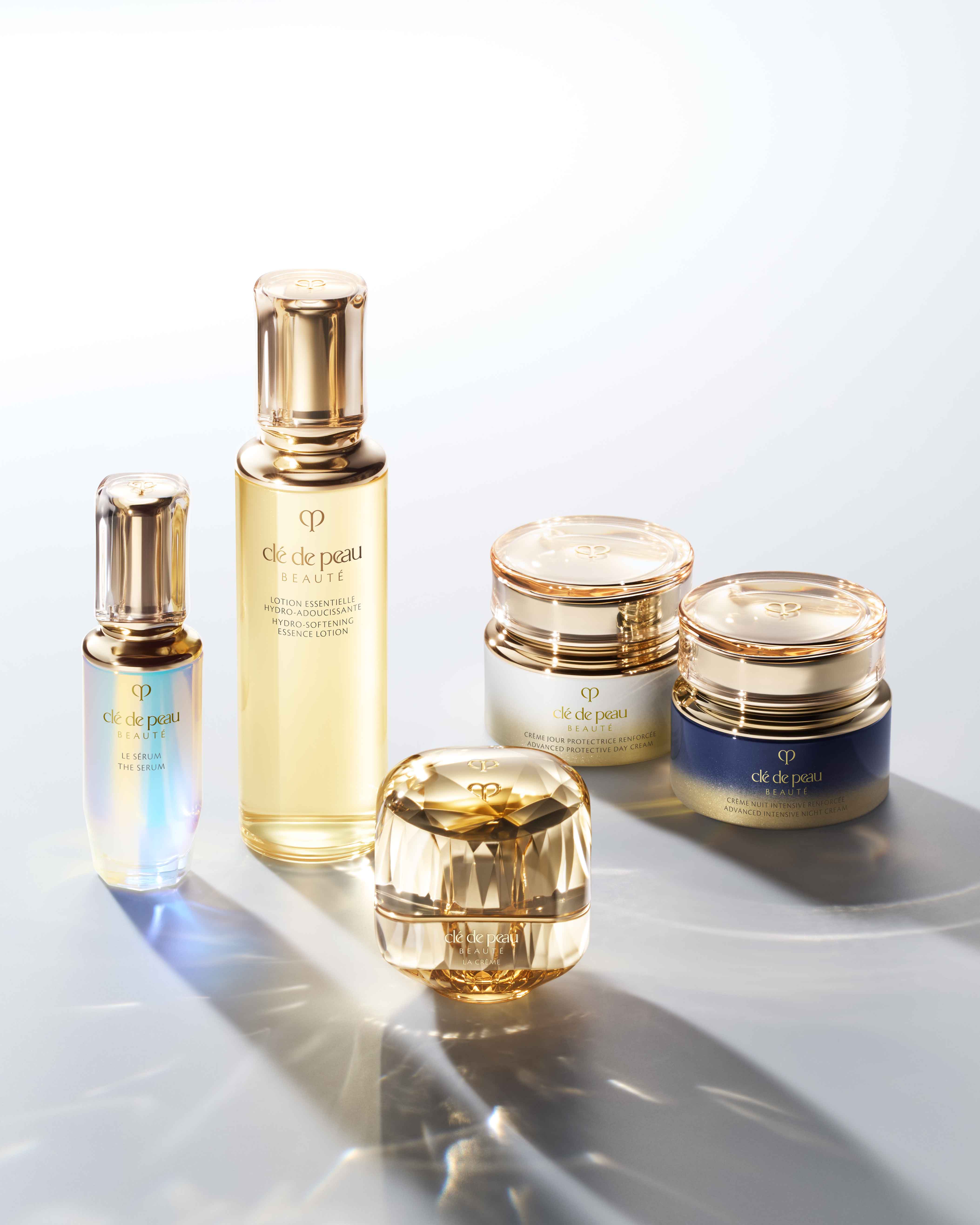 Photo of a collection of Clé de Peau Beauté's skincare products: "THE SERUM", "LA CRÈME", " HYDRO-SOFTENING ESSENCE LOTION", "ADVANCED PROTECTIVE DAY CREAM" and "ADVANCED INTENSIVE NIGHT CREAM". 